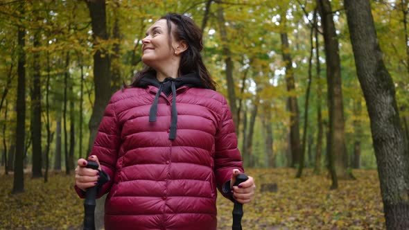 Panning Shot of Happy Mature Caucasian Woman Smiling Admiring Beauty of Autumn Nature in Forest