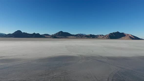 An aerial drone shot reveals smooth water covering the white slat of the Bonneville Salt Flats and d