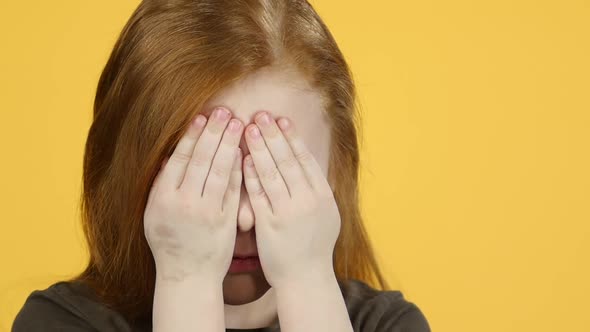 Close-up Child with Red Hair Have Fun Covers Her Face with Hands. Slow Motion