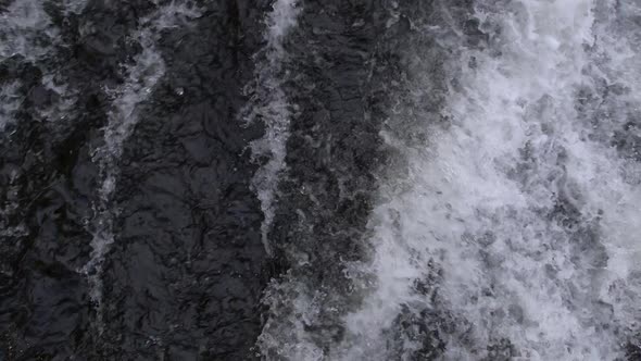 Shot of water before it goes over a waterfall and following it over the falls