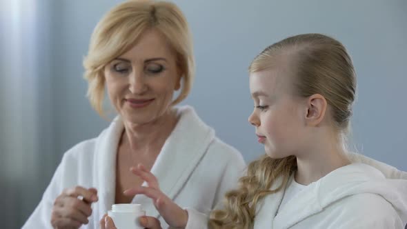 Grandmother and Granddaughter Applying Face Cream and Smiling, Skin Care, Beauty