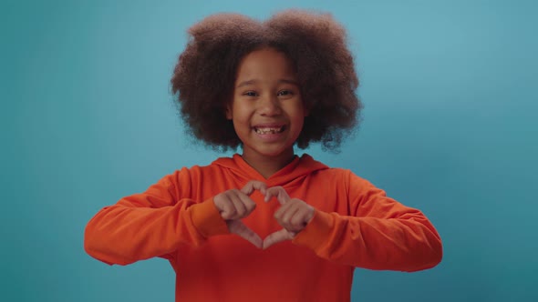 Smiling African American girl making heart shape with fingers looking at camera