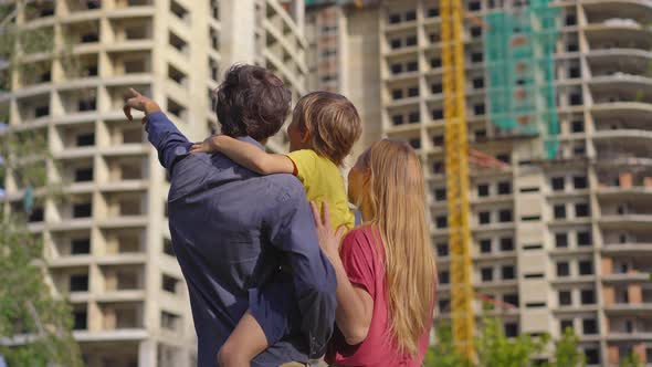 A Family Father Mother and Son Look at a Tall Building That is Under Construction