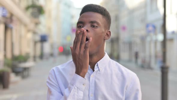 Sleepy African Man Yawning While Standing Outdoor