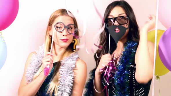 Beautiful women having fun dancing using props in party photo booth