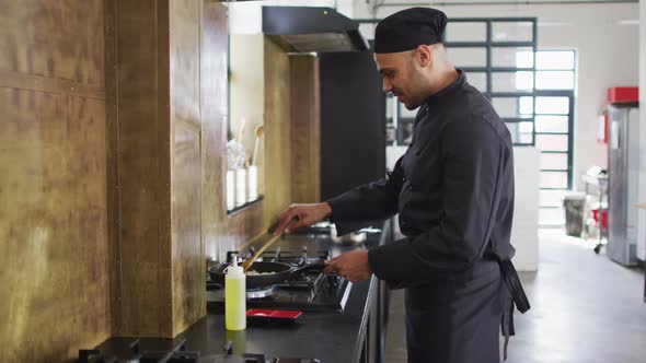 Caucasian male chef frying vegetables on a pan