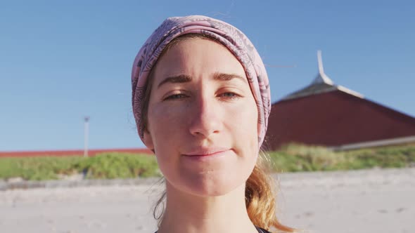 Caucasian woman looking at camera and smiling on the beach and blue sky background