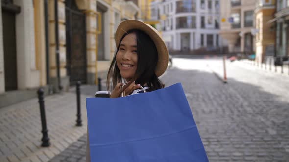 Asian Girl with Shopping Bags Walking Along Street