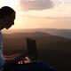 Silhouette of a Man Working on a Laptop Outdoors at Sunset - VideoHive Item for Sale