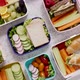 Shot of School Lunchboxes with Various Healthy Nutritious Meals on Stone Background - VideoHive Item for Sale