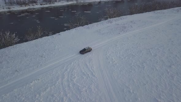 Drone shooting of river against background of a forest and a bridge, a car