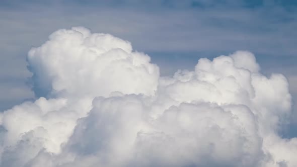 Time lapse footage of fast moving white puffy cumulus clouds on blue clear sky.