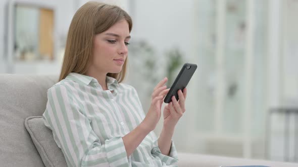 Serious Young Woman Using Smartphone at Home 