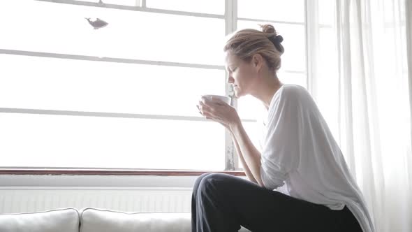 Woman sitting at a window drinking tea