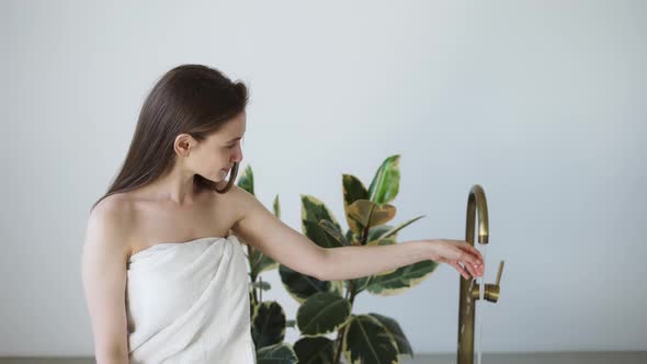 Woman Taking a Bath at Home Checking Temperature Touching Running Water with Hand