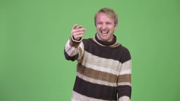 Studio Shot of Happy Handsome Man Laughing While Pointing Finger