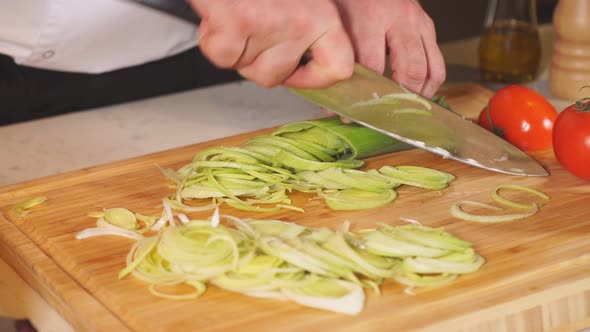Professional Chef in a Commercial Kitchen Is Slicing Green Vegetables