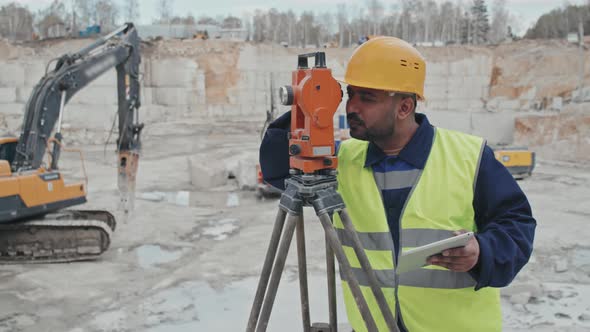 Quarry Worker Using Surveying Measuring Equipment