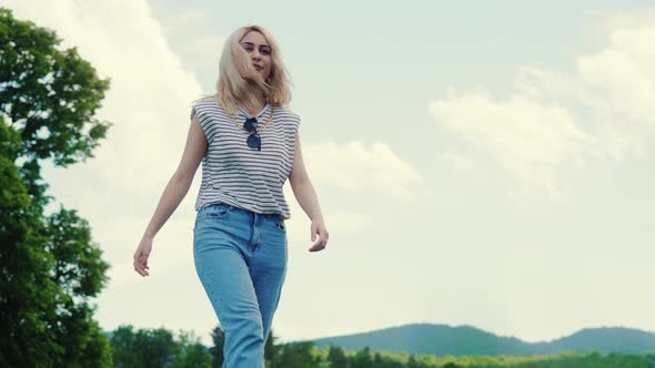 Caucasian Blond Girl Walking in the Park and Enjoying the Fresh Air and Beautiful Nature Mediumfull