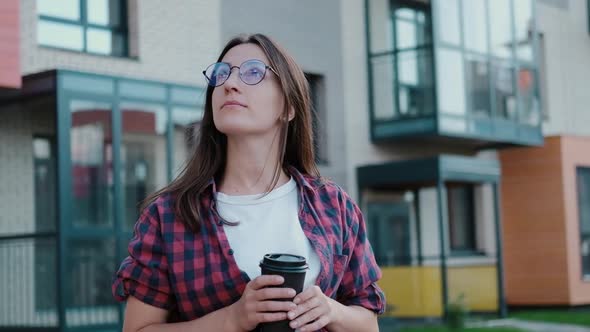 Young Attractive European Girl with Coffee While Walking Looks Around