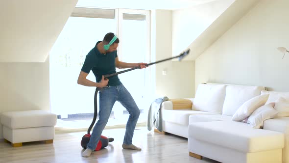 Man with Vacuum Cleaner and Headphones at Home