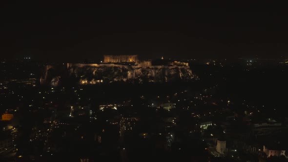 Aerial view of the parthenon temple on acropolis hill at night in Athens.