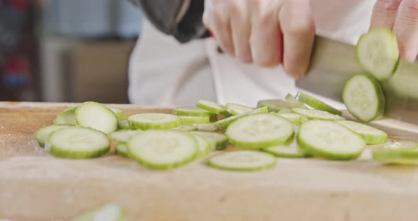 Slow motion close up of a chef knife slicing a cucumber