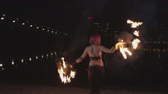 Woman Performing Dance with Flaming Fans at Dusk