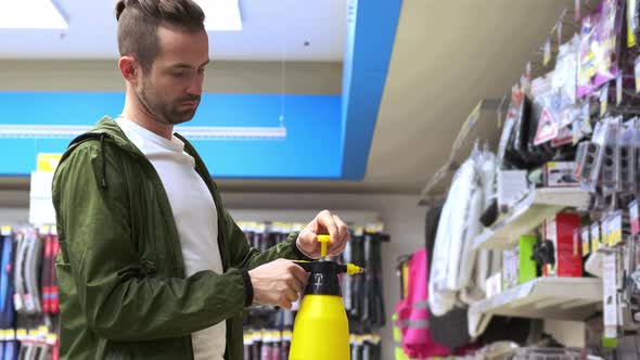 Young Man is Buying a Spray Bottle in Special Store