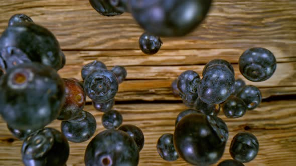 Super Slow Motion Detail Shot of Fresh Blueberries Falling on Wooden Table at 1000Fps