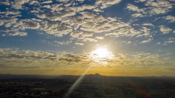 Aerial hyperlapse of bright sunrise with fluffy clouds over California City