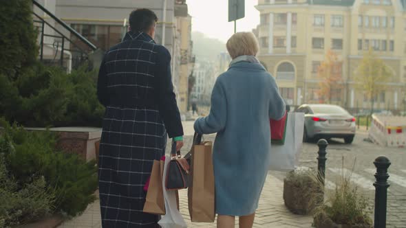 Rear View of Mature Women Carrying Many Shop Paper Packages Outdoors