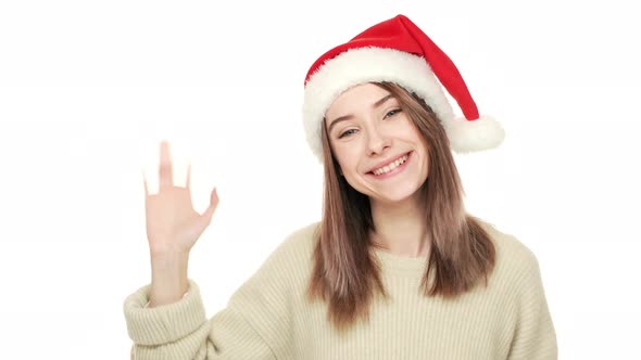 Happy Portrait of Attractive Young Woman in Santa Claus Red Hat Greeting People Waving Hand Enjoying