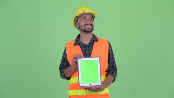 Happy Young Bearded Persian Man Construction Worker Thinking While Showing Digital Tablet