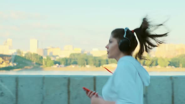 A Beautiful Girl in a White Sweater and Headphones Is Preparing for a Morning Run.