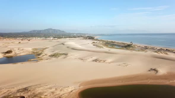 Drone Flies Going Through the Sand Dunes Towards the Sea.