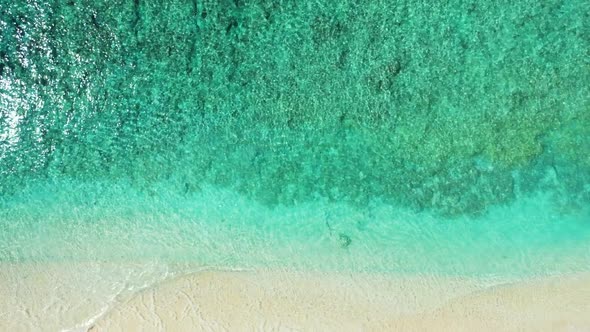 Aerial drone shot scenery of exotic resort beach break by shallow ocean and white sandy background o
