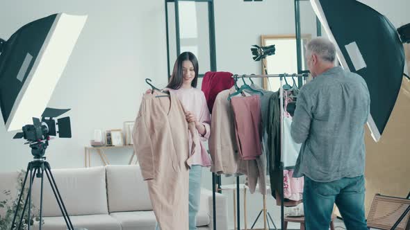 Young Woman is Choosing Clothes in the Photo Studio