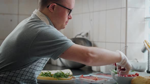 Caucasian man with down syndrome preparing a sandwich in commercial kitchen. Shot with RED helium ca