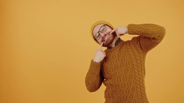 European Bearded Man Touching Corners of His Mouth and Smiling Medium Studio Shot Yellow Background