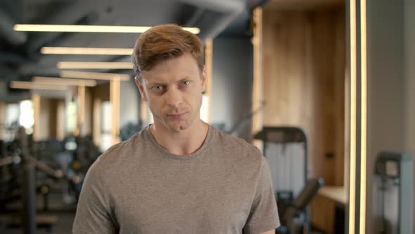 Serious Fitness Man Showing Thumb Up in Sport Club. Sportsman Standing at Gym