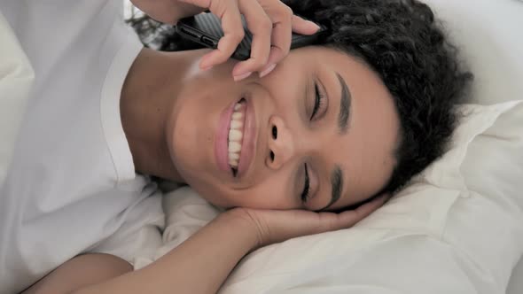 African Woman Talking on Phone in Bed
