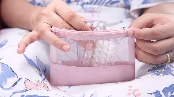Women Hand Putting Birth Control Pills in Small Bag