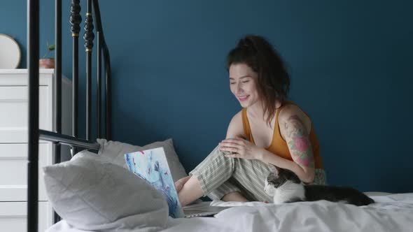 Pretty Woman Chatting Online at Home with Friends Together with Her Cat