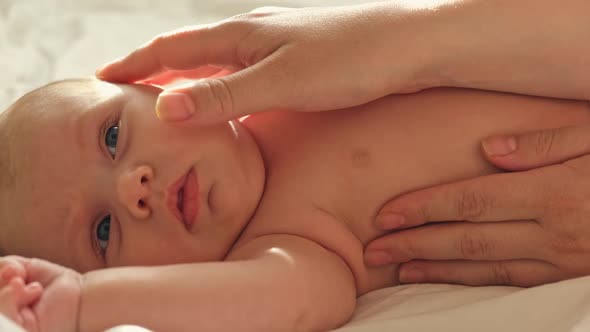 Close Up Shot Hands Of Mother Massaging Baby Face. Woman Gently Stroking and Touching Infant Baby.