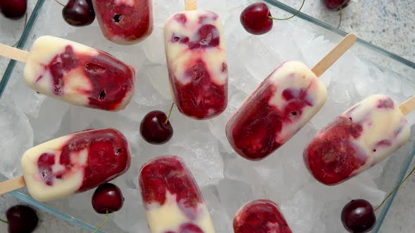 Homemade, Delicious, Cherry and Milk Ice Cream Popsicles Placed on Glass Tray Filled with Ice Cubes