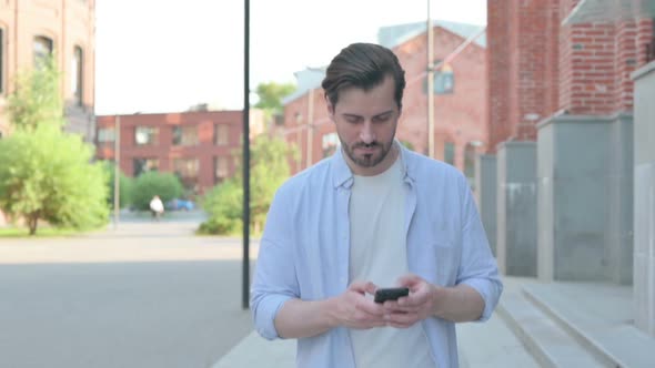 Walking Man Using Smartphone on Street