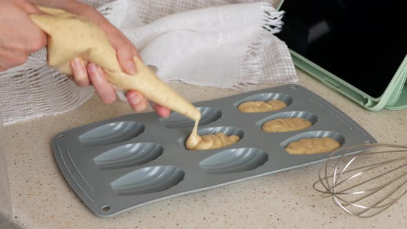 Person is filling the Madeleine mold with batter using pastry bag