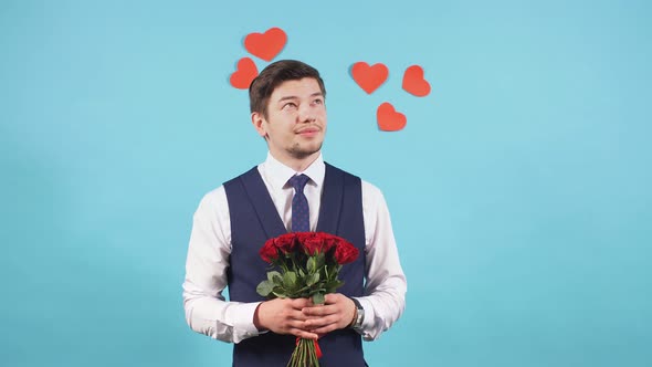 Positive Man in Tux with Red Roses Isolated Over Blue Background.