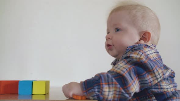 Small Baby Nibbles Orange Toy Standing at Table in Room